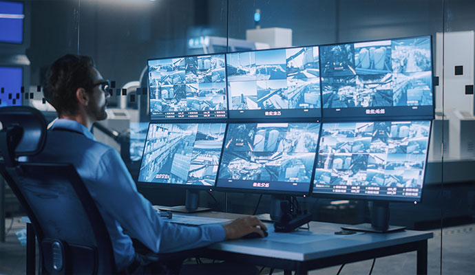 A security professional monitoring live surveillance feeds on multiple screens