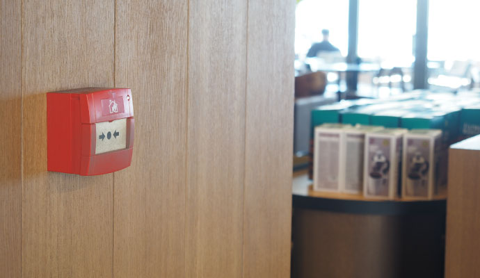 Fire alarm call point on wood paneled wall