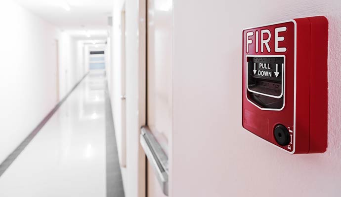 Fire alarm pull station mounted on wall in office hallway