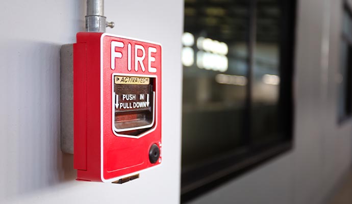 Red fire alarm pull station mounted on wall inside commercial building