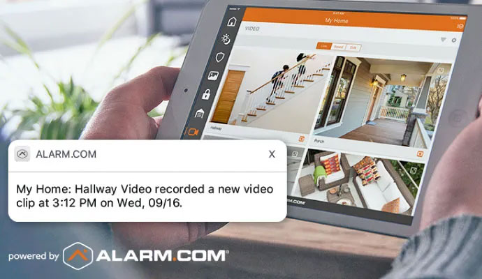 Person monitoring live security video feed on tablet using Alarm.com app