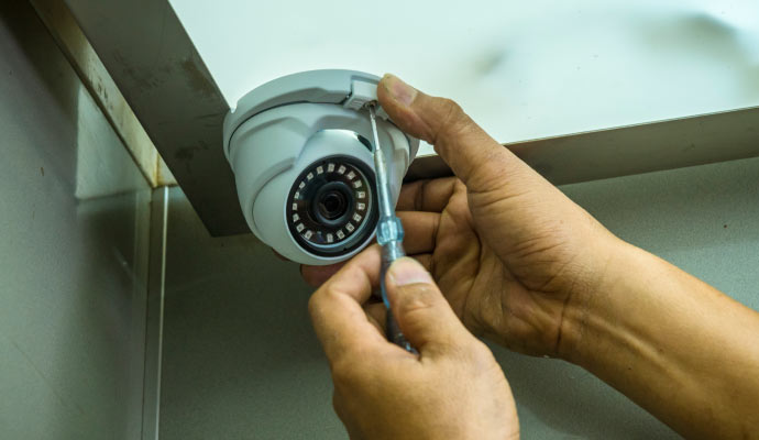 Person installing security camera with equipment