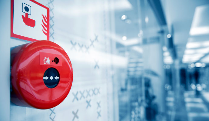 Red manual fire alarm call point on wall