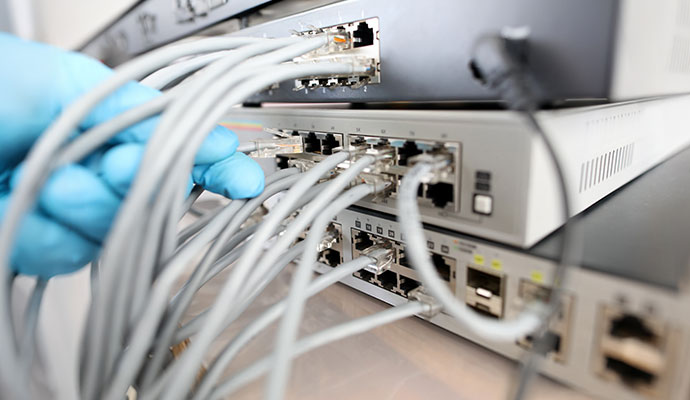 A person connecting fiber optic cables to a professional network switch.