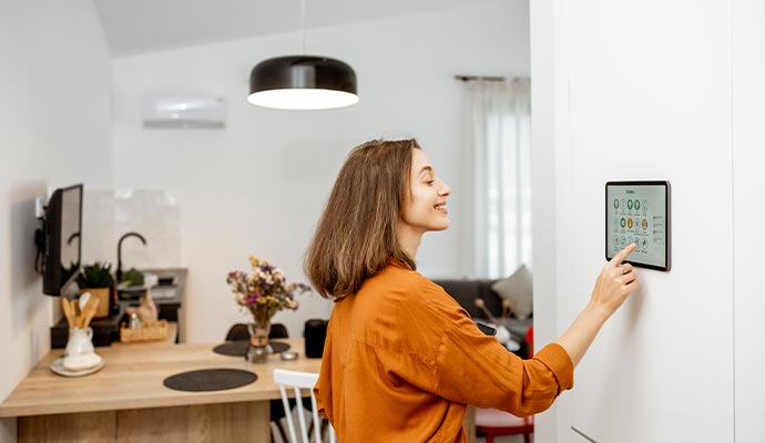 Woman using smart home control panel to manage lighting climate and connected home automation features