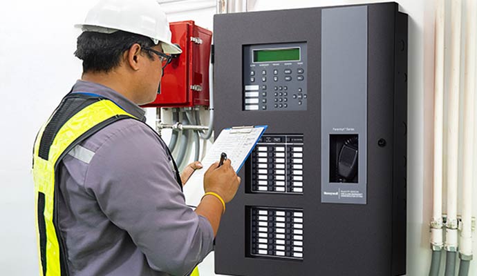 Technician inspecting Honeywell Farenhyt Series fire alarm control panel